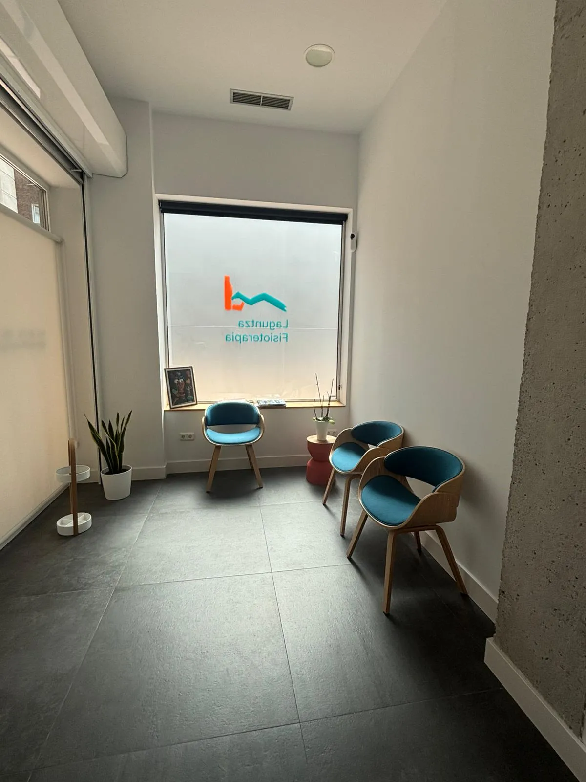 Sala de espera de Laguntza Fisioterapia con sillones y el logotipo, Urnieta